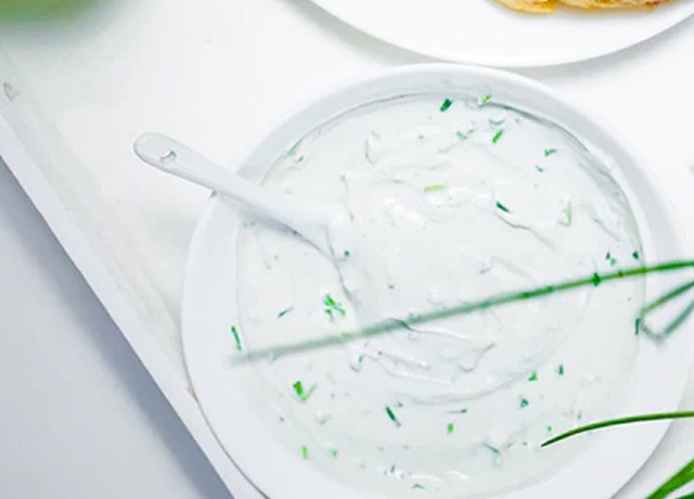 top-down view of tzatziki sauce, garnished with chives with a serving spoon