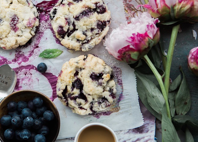Top-down view of blueberry cookies surrounded by flowers and a bowl of fresh blueberries